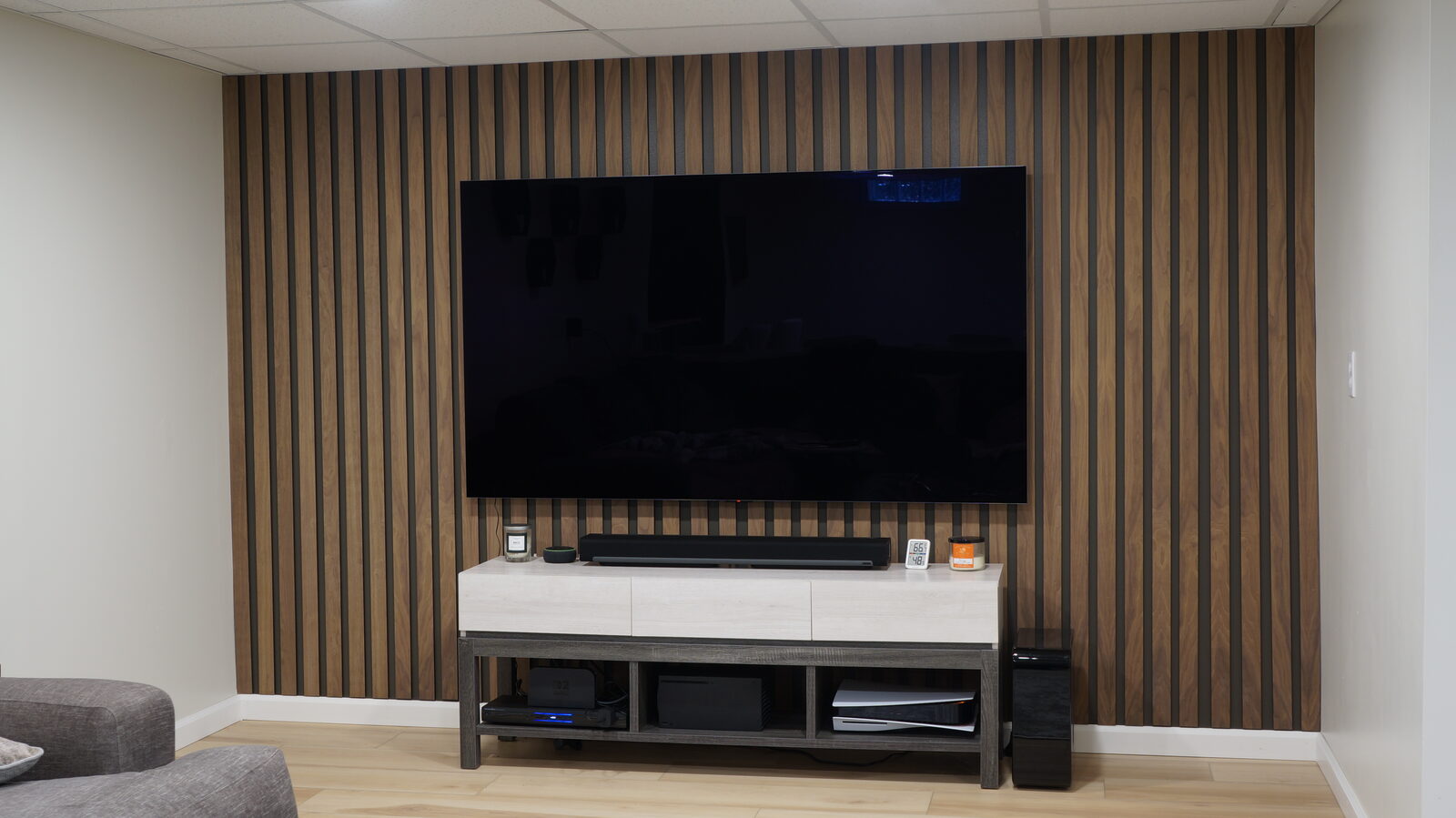Walnut wood slat accent wall behind a mounted television, styled with a media console